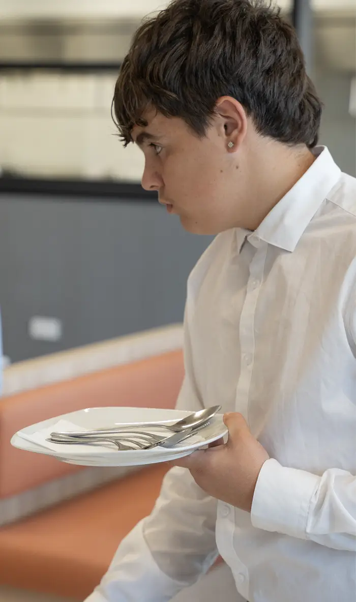 Alumno de hostelería practicando el servicio de mesa con cubertería para obtener su certificado profesional en el centro Nova FP23 en Madrid.
